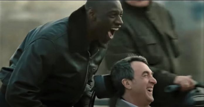 영화 언터처블의 한 장면으로 드리스가 필립의 휠체어를 밀면서 달리고 있다.