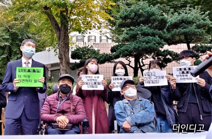 지난 10월 15일 국민연금공단 장애심사센터 앞에서 열린 기자회견에서 참가자가 제도권 밖의 장애를 인정하라는 등의 피켓을 들고 있다./사진=더인디고