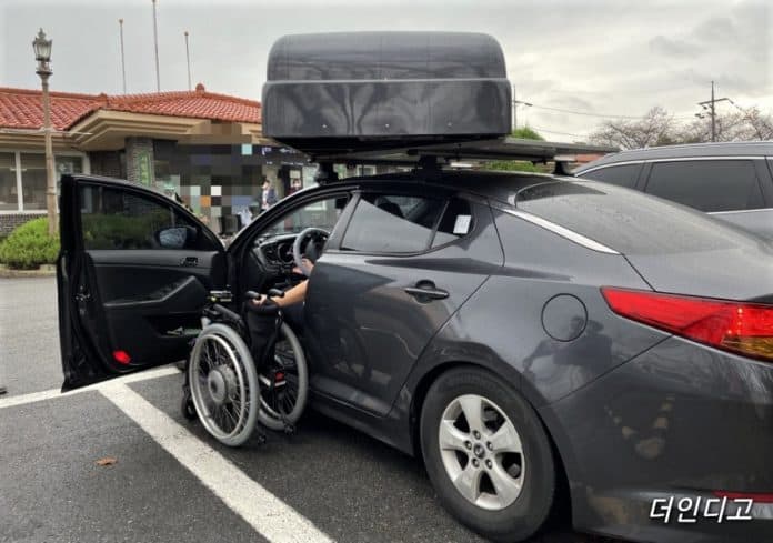 ▲장애인 운전자가 자동차 루프박스에서 휠체어를 내리고 있다. ⓒ더인디고
