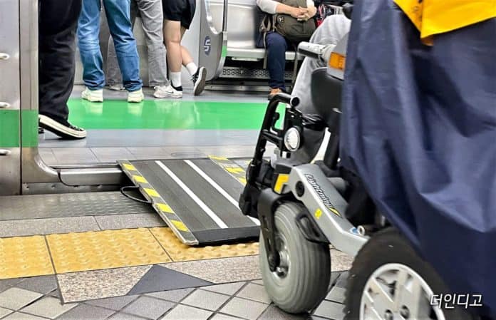 ▲전동휠체어 사용자가 지하철 이동식 안전 발판을 이용해 승차 하고 있다. ©더인디고