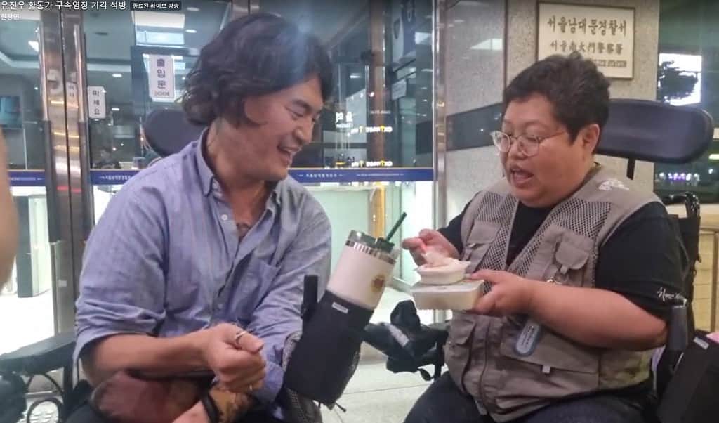 ▲지난 20일 밤 유진우(사진 왼쪽) 전장연 활동가가가 남대문경찰서에서 조사를 받고 나오면서 두부를 먹고 있다. /사진=전장연 페이스북 캡처