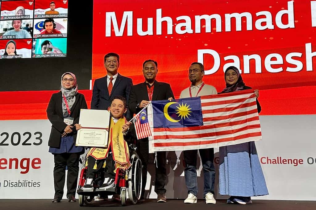 ▲2023 글로벌IT챌린지에서 종합 우승한 무함마드 나지르 다니쉬 학생이 상장과 말레이시아 국기를 들고 환하게 웃고 있다. 상은 LG전자 이일환 중아지역 대표(사진 뒷줄 왼쪽에서 두 번째)가 수여했다. ⓒ한국장애인재활협회
